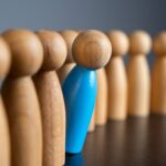 Holzmännchen in einer Reihe, wobei ein blaues Männchen aus der Reihe rausschaut. Mediationssituation